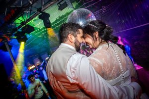 Pareja bensándose en su barra libre festival en una boda con bola de discoteca y luces