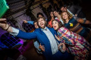 Grupo de amigos divertidos en una boda haciéndose un selfie